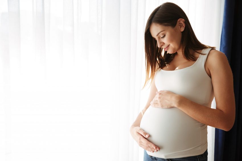 portrait of happy pregnant woman touching her belly scaled e
